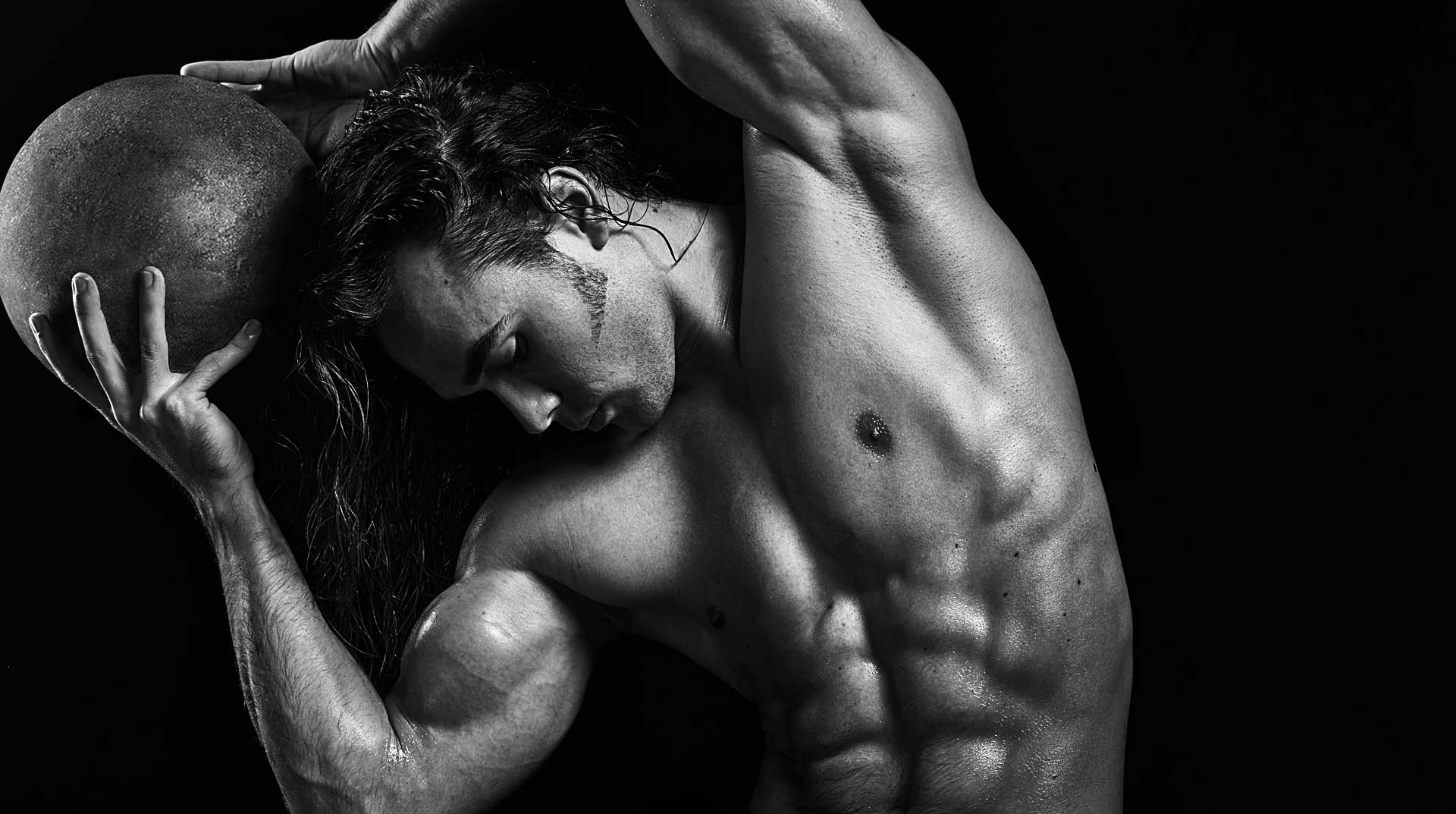 Black and white portrait of bodybuilder holding medicine ball