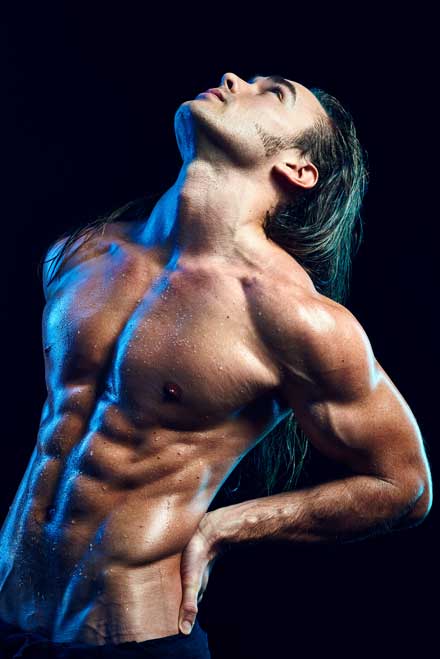 Bodybuilder with perfect abs in studio photo shoot