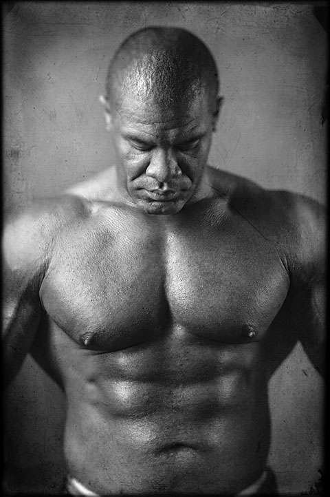 Bodybuilder with huge muscles and abs poses for studio portrait